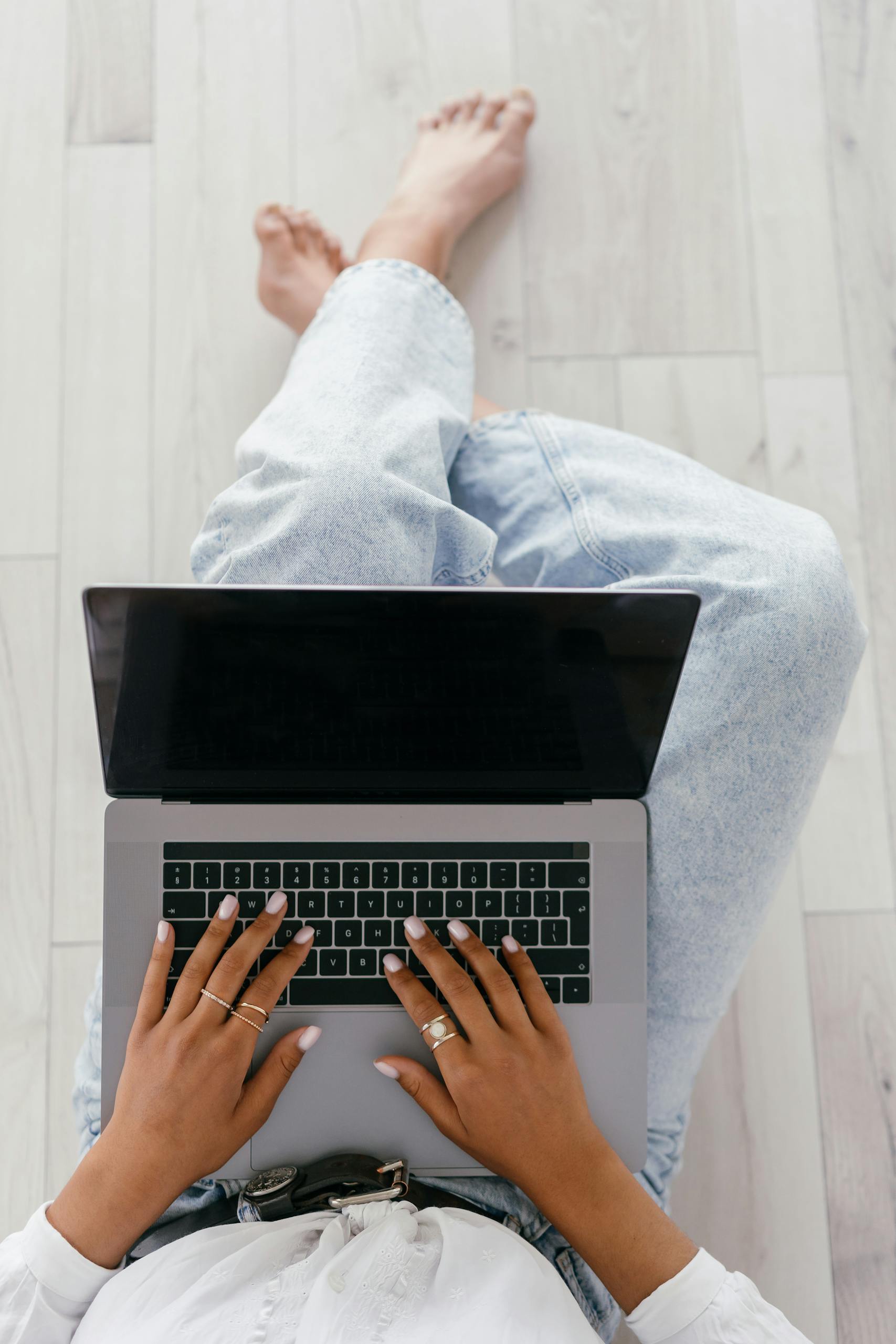 A Person in Blue Denim Jeans Using a Laptop